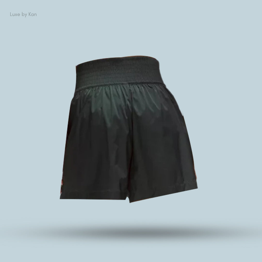Black athletic shorts with a smocked waistband, displayed against a light blue background, highlighting their sleek design.