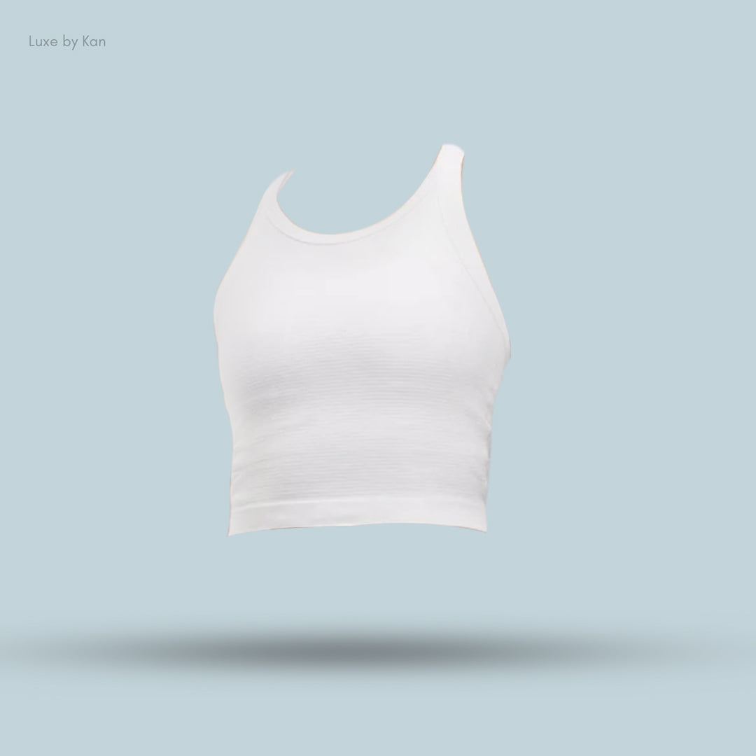 White cropped tank top displayed against a soft blue background, showcasing its sleek design and smooth fabric.