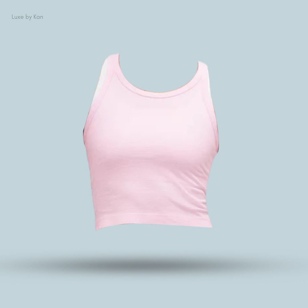 Light pink cropped tank top displayed against a soft blue background, showcasing a minimalist design without a model.