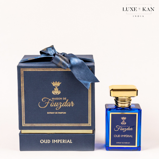 Maison de fouzdar oud imperial perfume bottle next to a luxurious blue box, adorned with a golden crown and satin ribbon.