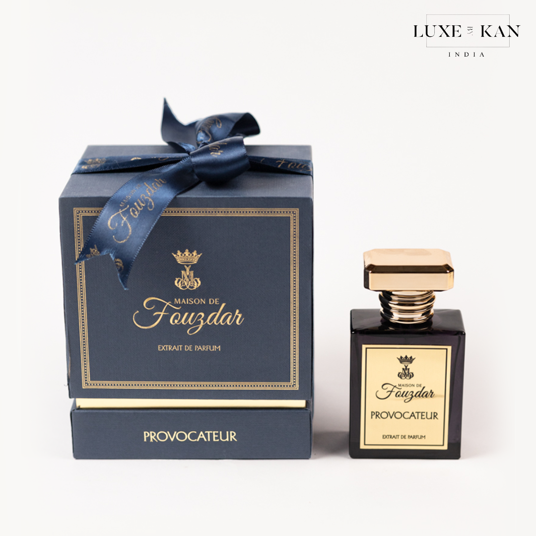 Maison de fouzdar provocateur perfume bottle next to a luxurious blue box, adorned with a golden crown and satin ribbon.