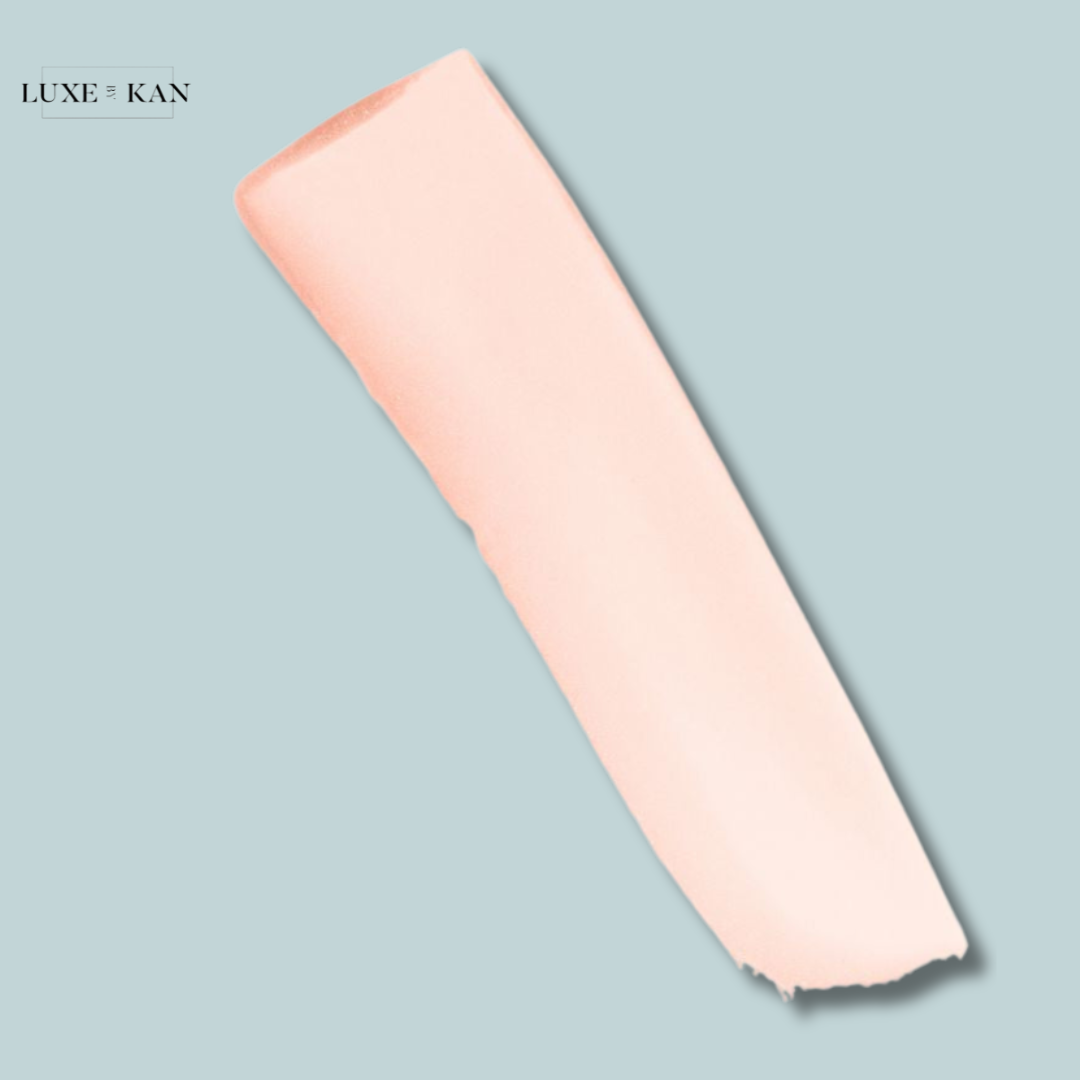 A creamy, light pink cosmetic swatch on a soft blue background, showcasing a smooth texture and elegant presentation.