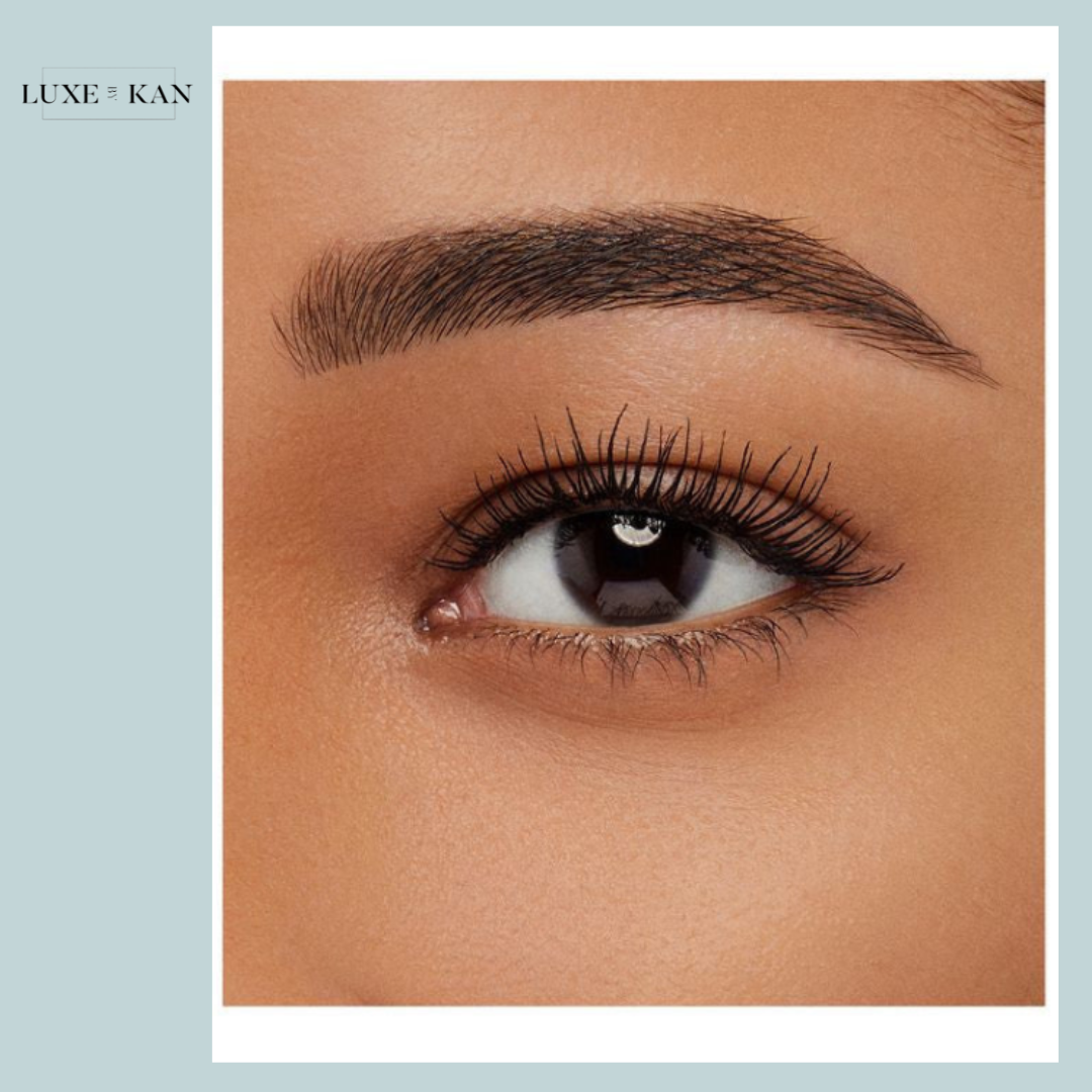 A close-up of a woman's eye showcasing long lashes, sculpted eyebrows, and smooth skin tone.