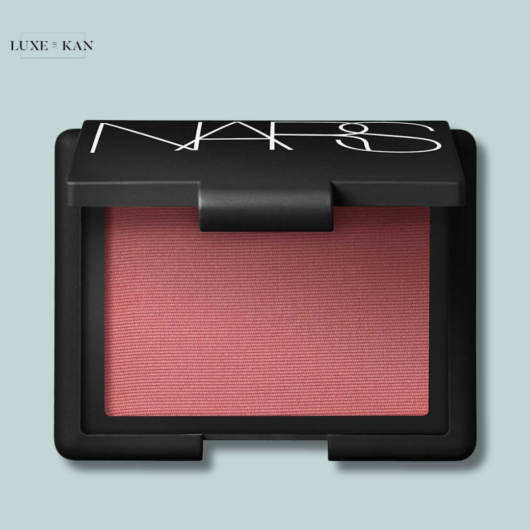 A close-up of NARS blush in a sleek black compact, featuring a soft pink pigment.