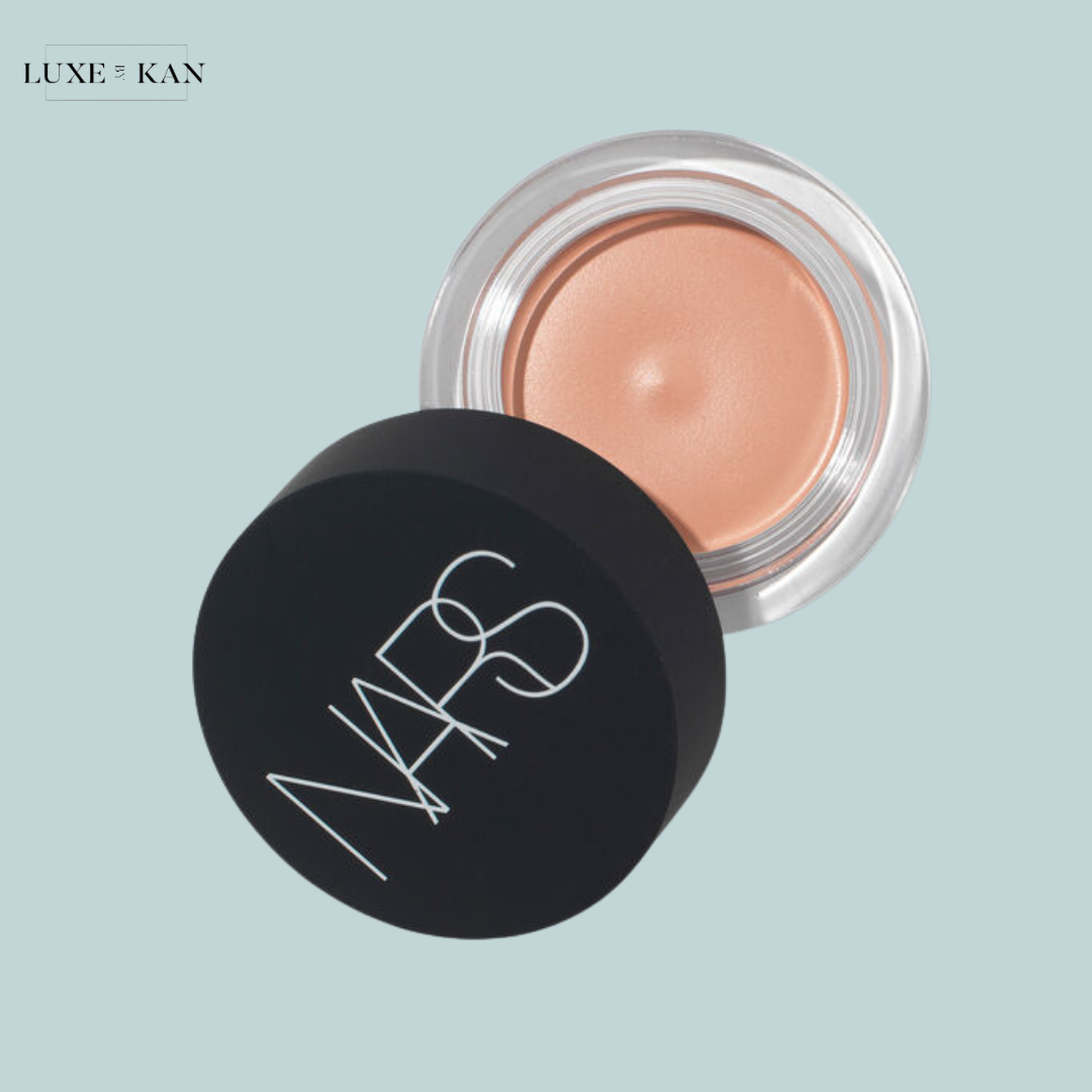 A NARS cosmetic product in a sleek, black container, slightly open to reveal a creamy, nude-colored product inside.