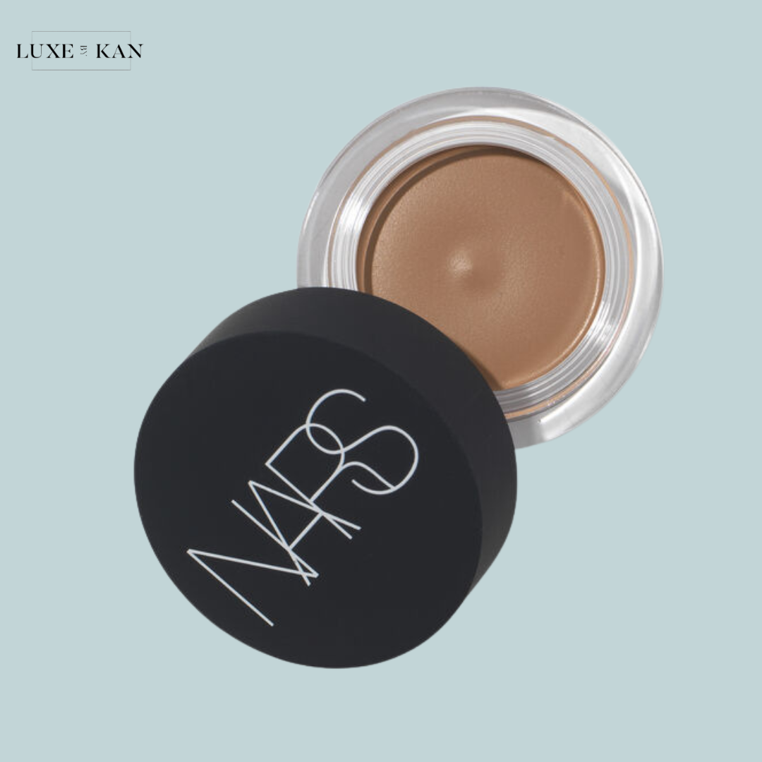 A NARS cream product in a clear jar with a black lid, showcasing a smooth, caramel-toned formula.