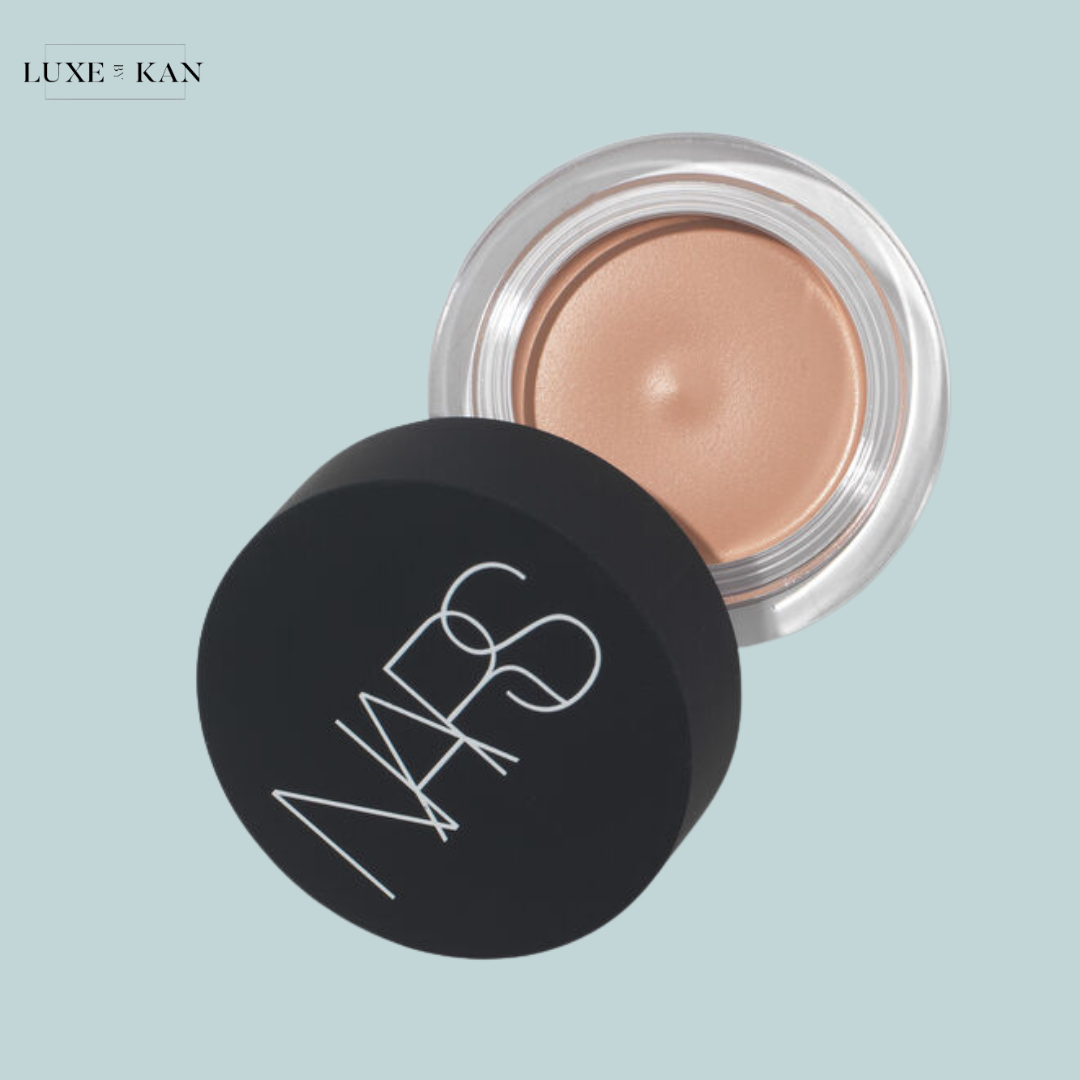 A NARS cream product in a clear container with a black lid, showcasing a soft beige shade.
