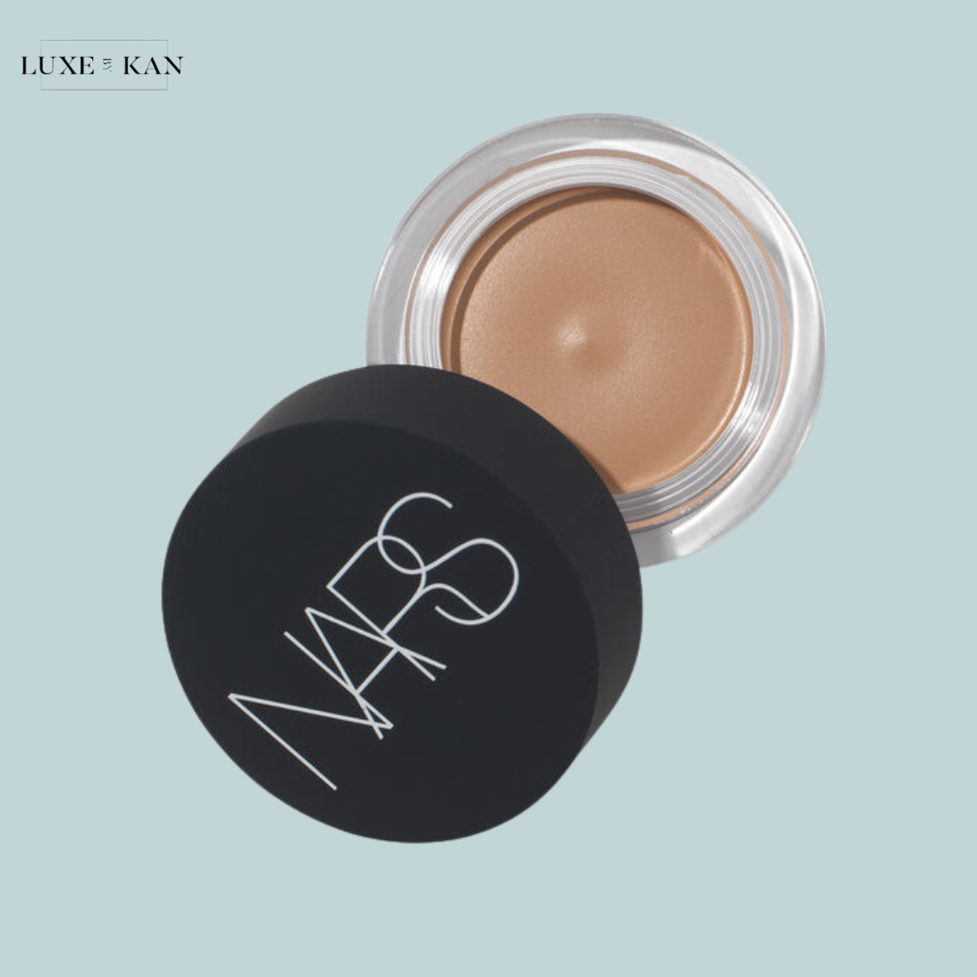A jar of NARS foundation, partially opened, displaying a creamy beige product inside.