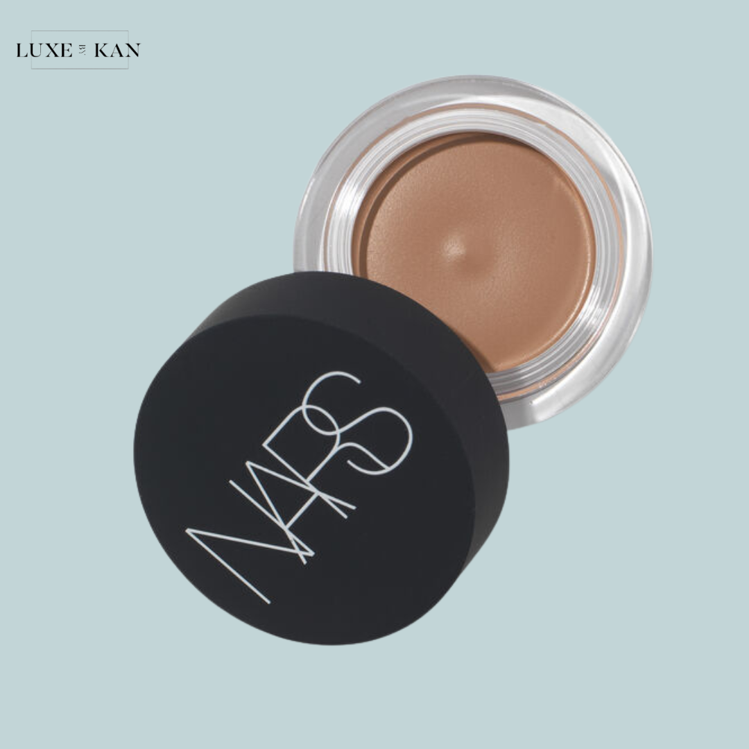 A NARS cosmetic jar with a sleek black lid, revealing a creamy bronze product inside.