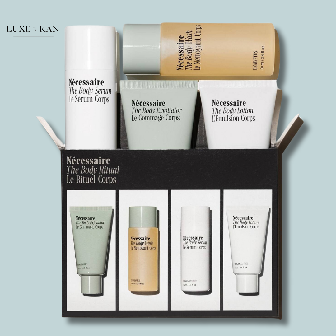 A flat-lay of the Nécessaire the body care ritual set featuring serum, exfoliator, wash, and lotion in minimalist packaging.
