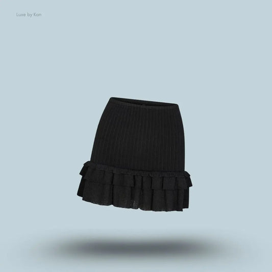 SKIMS Sheer Knit Ruffle Mini Skirt in Onyx, flat lay on light blue background