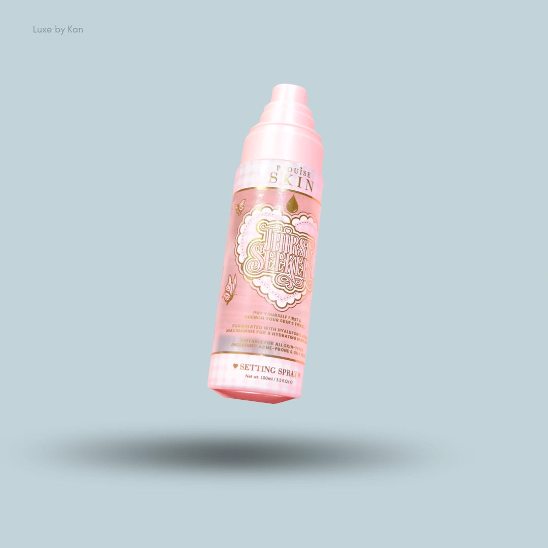 P Louise Skin Thirst Seeker Setting Spray in a pink bottle with gold butterfly accents, 100ml, over a blue background.