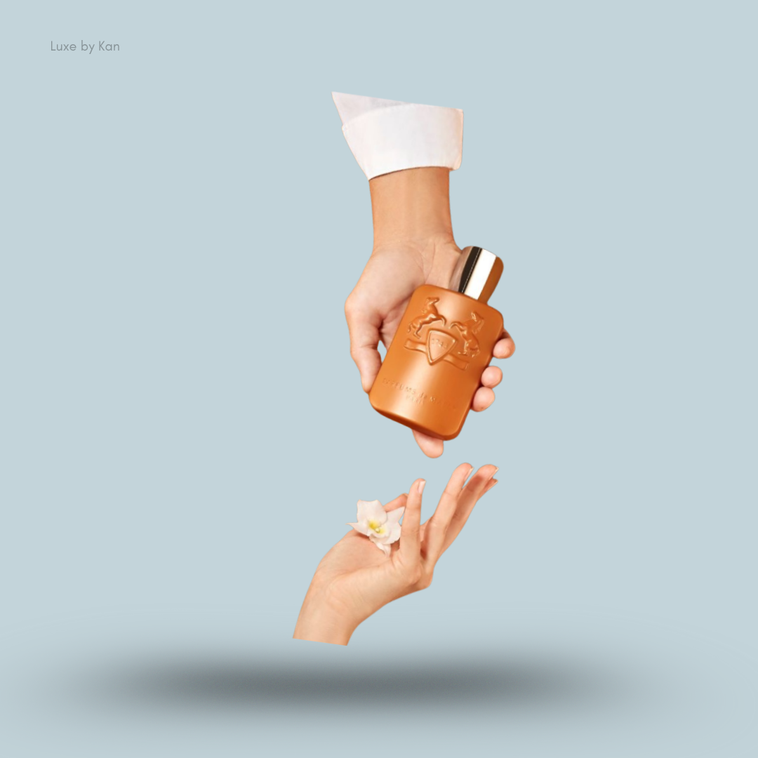 Parfums de Marly Althair bottle held above a hand, a flower below.