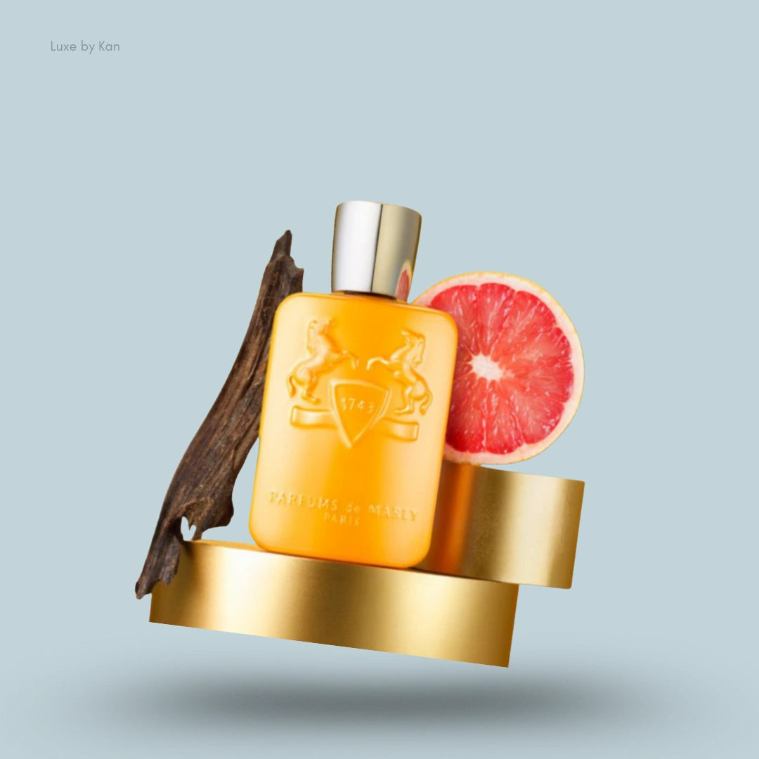 Parfums de Marly Perseus eau de parfum spray bottle, reddish grapefruit half, weathered wood, and gold stand.
