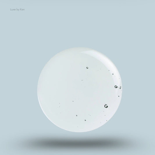 Close-up of a clear, jelly-like sphere on a pale blue background, representing anti-dandruff shampoo; a shadow is visible directly below the sphere.