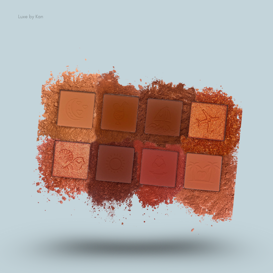 Eight-pan eyeshadow palette floating above a pile of pressed pigment powder, featuring travel-themed embossments.