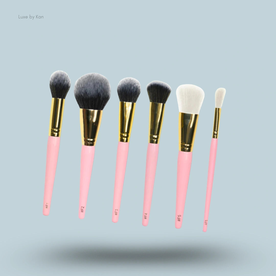 Cosmetic brush set includes six brushes with pink handles, gold ferrules, and a variety of brush head shapes and sizes.
