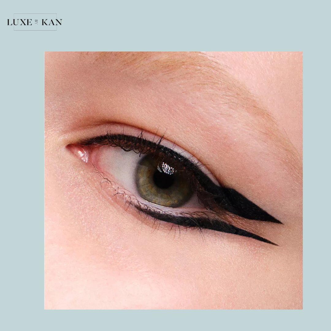 Close-up of an eye showcasing dramatic black winged eyeliner, enhancing its green iris against a soft blue background.
