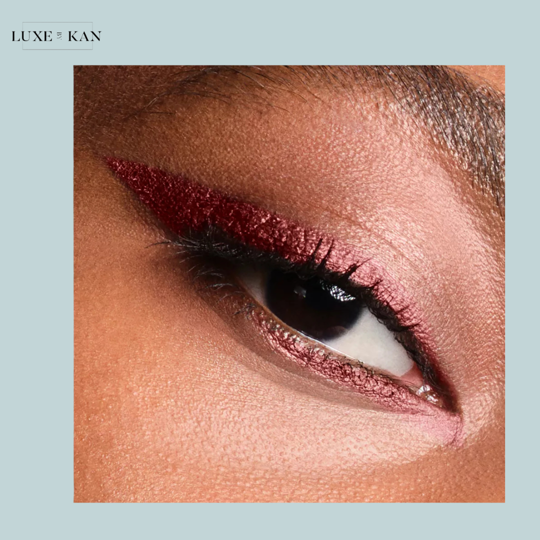 Close-up of a woman's eye featuring a bold burgundy winged eyeliner and shimmery eyeshadow, showcasing beauty and elegance.