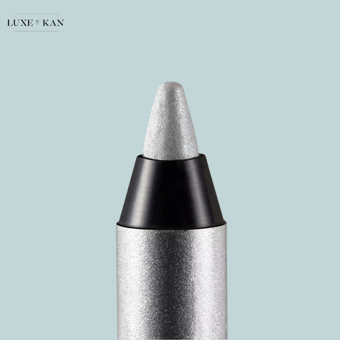 Close-up of a silver eyeliner pencil with a sleek design, featuring a pointed tip against a soft blue background.
