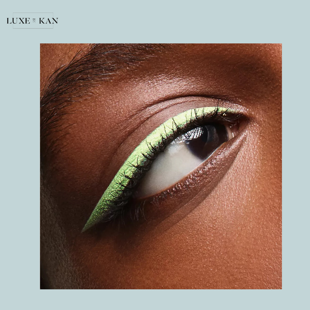 Close-up of an eye with bold, vibrant mint green eyeliner, showcasing defined lashes and flawless dark skin.