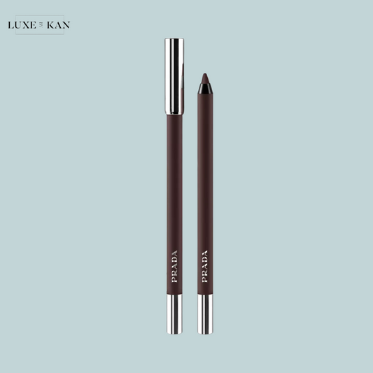 Two Prada lip pencils in a deep brown shade, one capped and one with a sharpened tip, set against a soft blue background.