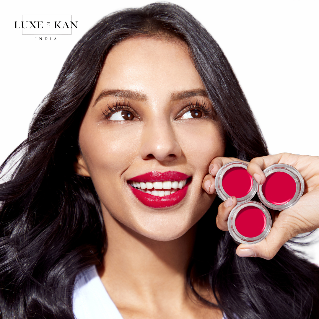 A woman with long, wavy hair holds three laali lip paint pot lip color, showcasing a beauty brand’s vibrant product.