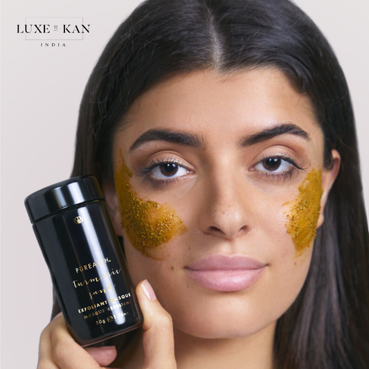 A girl has applied the Purearth Turmeric Sand Exfoliant Face Mask on her cheeks and is holding the bottle in her hand.