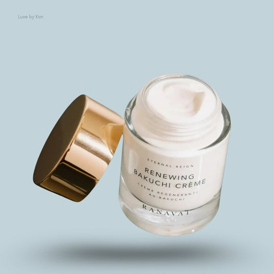 A clear glass jar of Renewing Bakuchi Crème by Ranavat, with a gold lid, partly opened, displaying a creamy product inside.