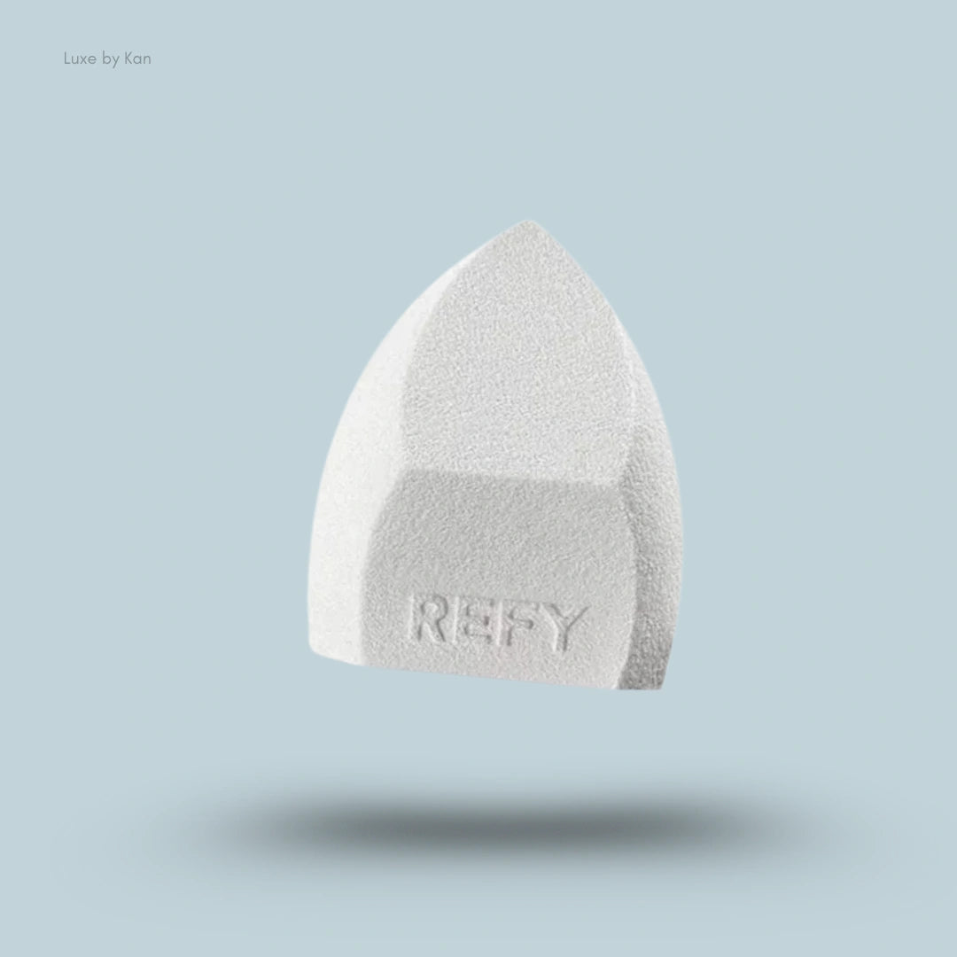 Close-up of a light gray Refy beauty sponge, displaying a textured surface and the brand name.