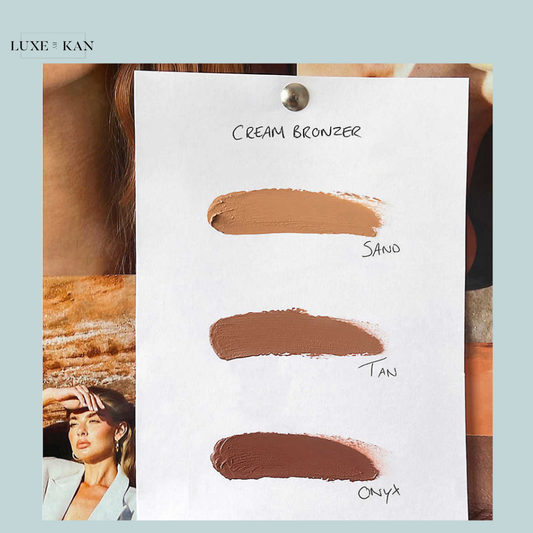 Cream bronzer swatches in three shades: Sand, Tan, and Onyx displayed on a piece of paper.