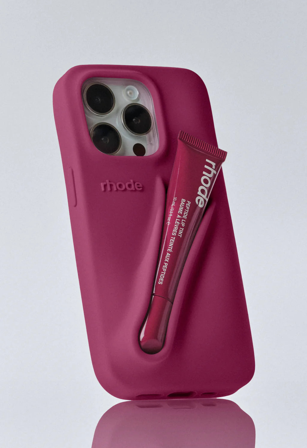 Raspberry iPhone case with Rhode logo and tube of Rhode peptide lip tint in case holder, against a white background.