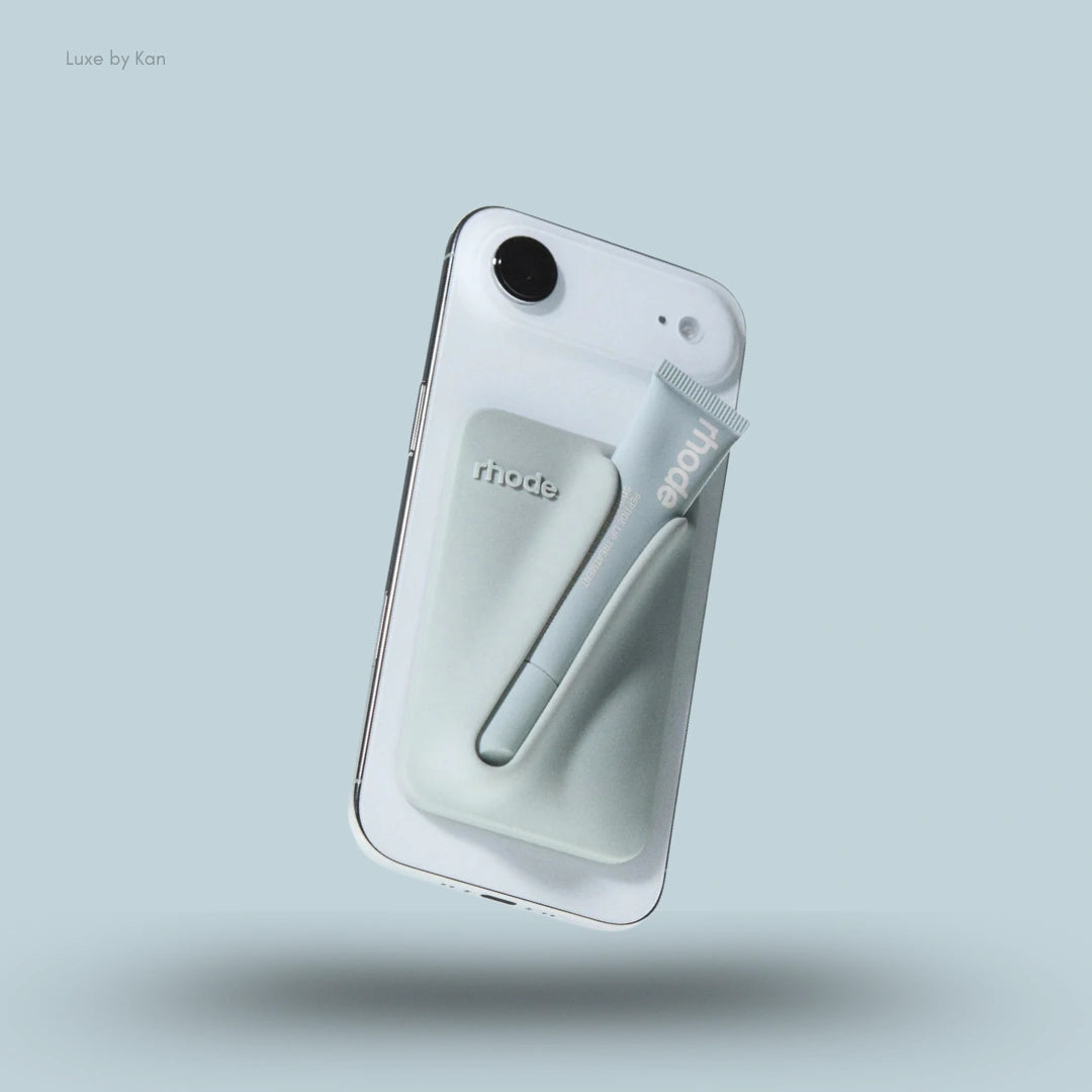 A grey Rhode Snap-On Lip Balm Holder for Iphone 17 with a pale blue Peptide Lip Treatment tube secured on the back.