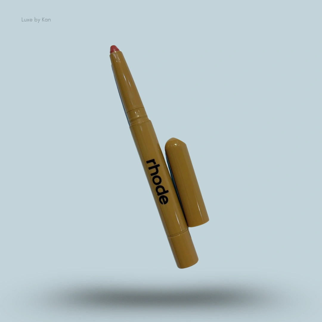 Rhode peptide lip shape liner with cap off, revealing red pigment. The pencil is light brown with the brand name in black lettering.