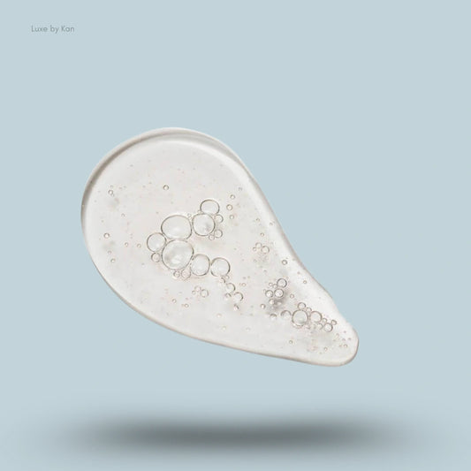 Close-up of a droplet of Shani Darden Skincare Cleansing Serum, revealing a clear formula containing distinct air bubbles.