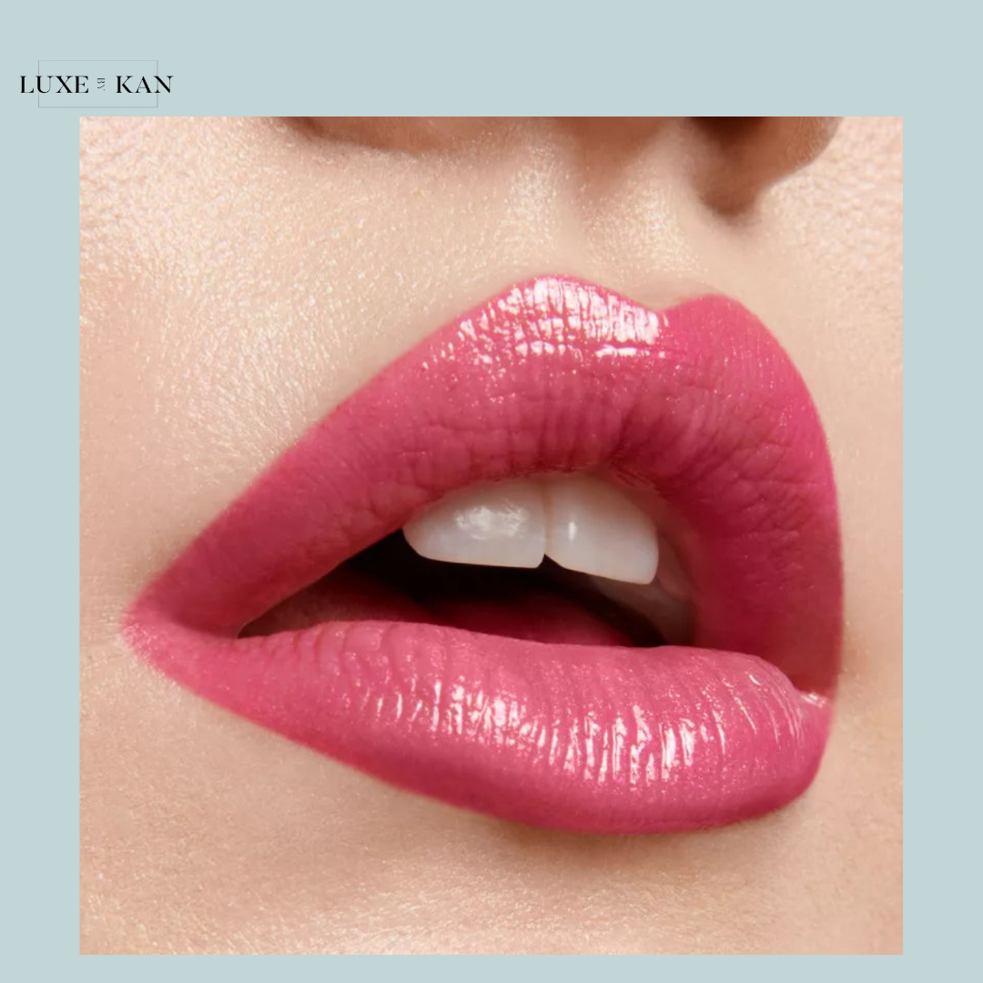 Close-up of glossy, full lips in a vibrant pink shade, highlighting a smooth texture and subtle shine. Background is a light blue.