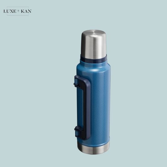 Blue insulated thermos with a stainless steel lid and a black foldable handle.