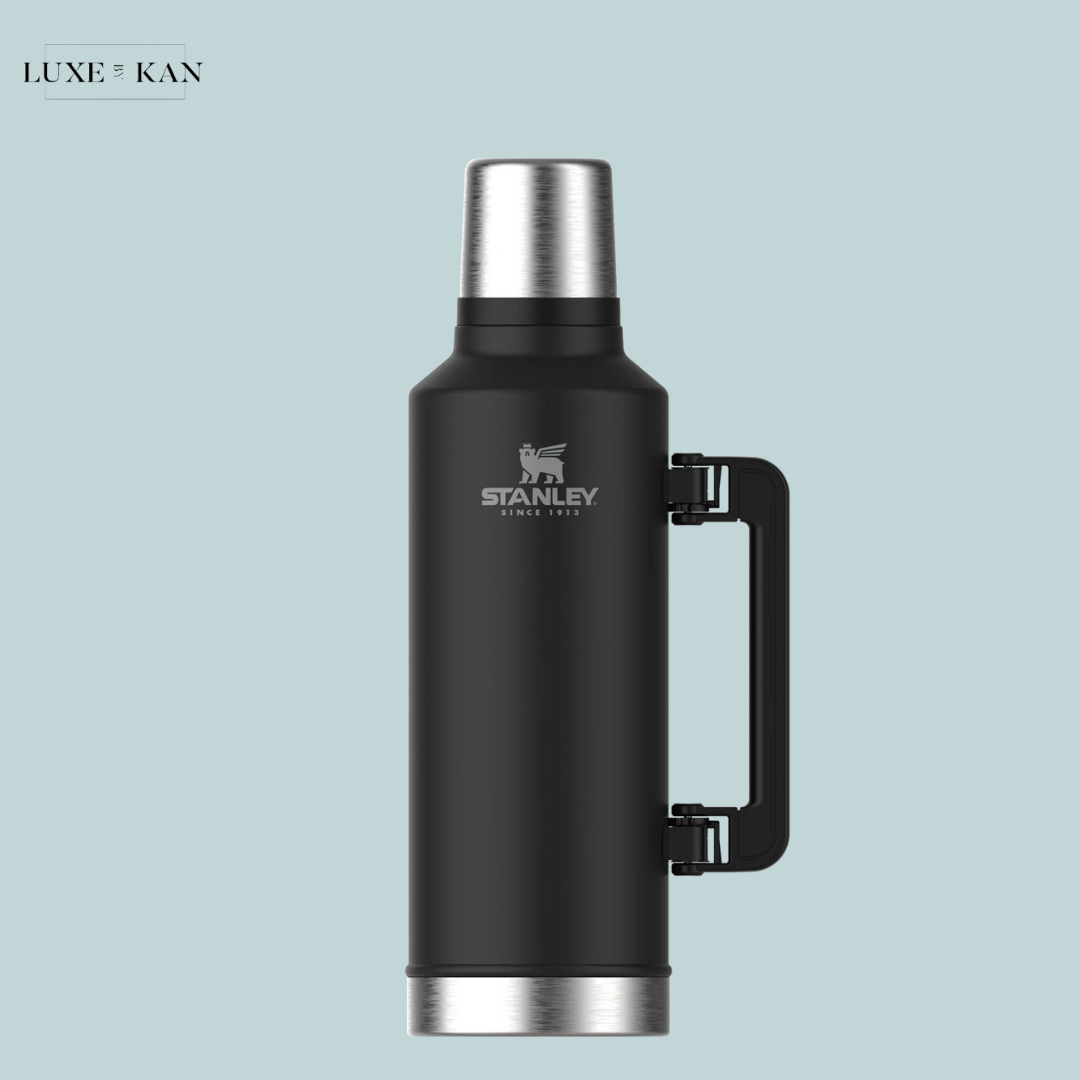 Black stainless steel thermos with a silver top and handle, featuring the Stanley logo.