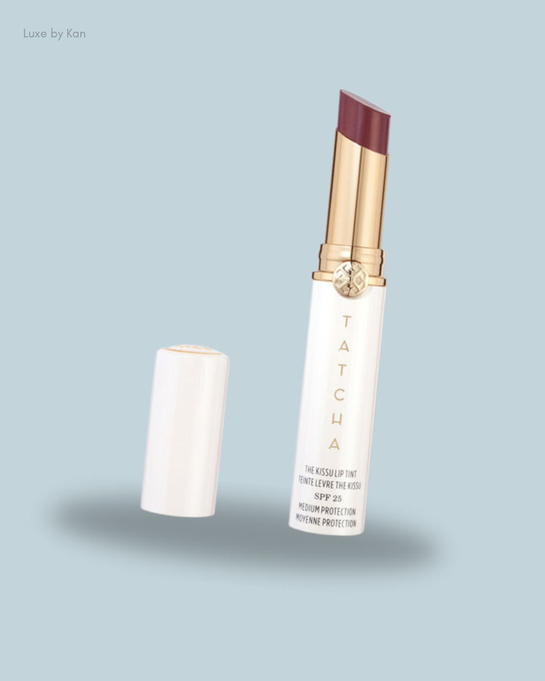 A Tatcha Kissu Lip Tint with SPF 25 in a sleek white tube, partially opened to reveal a rich plum shade.