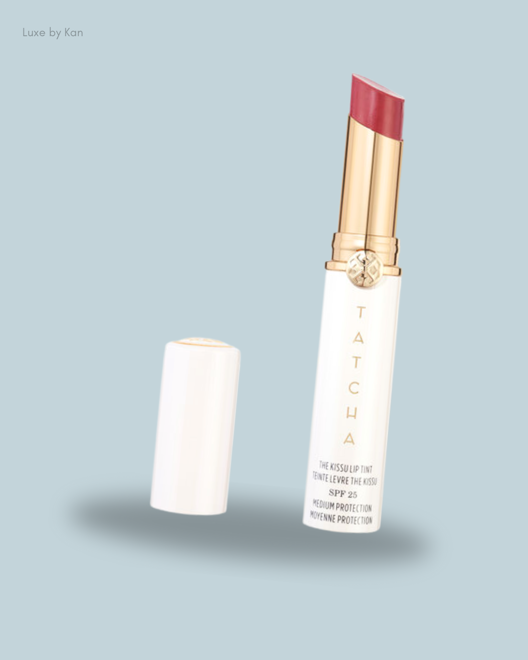 A tube of Tatcha's Kissu Lip Tint in rosy pink, with SPF 25, positioned beside its cap.