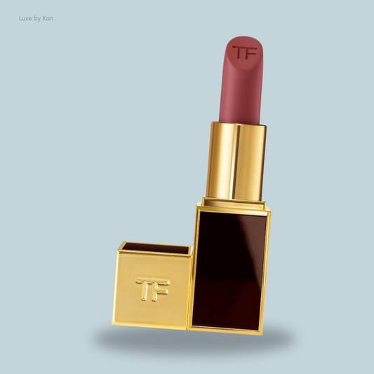 A luxurious Tom Ford lipstick in a gold and maroon case, featuring the "TF" logo on both the bullet and the base.