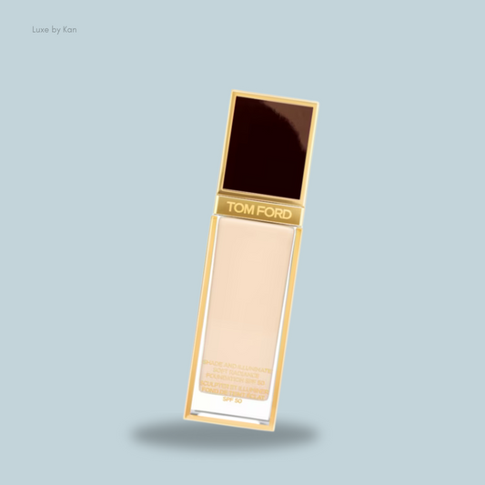 A elegant Tom Ford foundation bottle with a sleek gold design, featuring a dark brown cap and SPF 50 label.