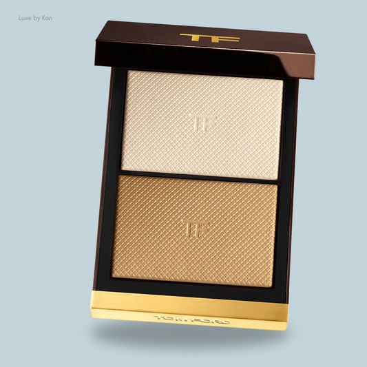 Tom Ford highlighter palette featuring two shades: a shimmering light beige and a warm gold, housed in an elegant brown and gold compact.