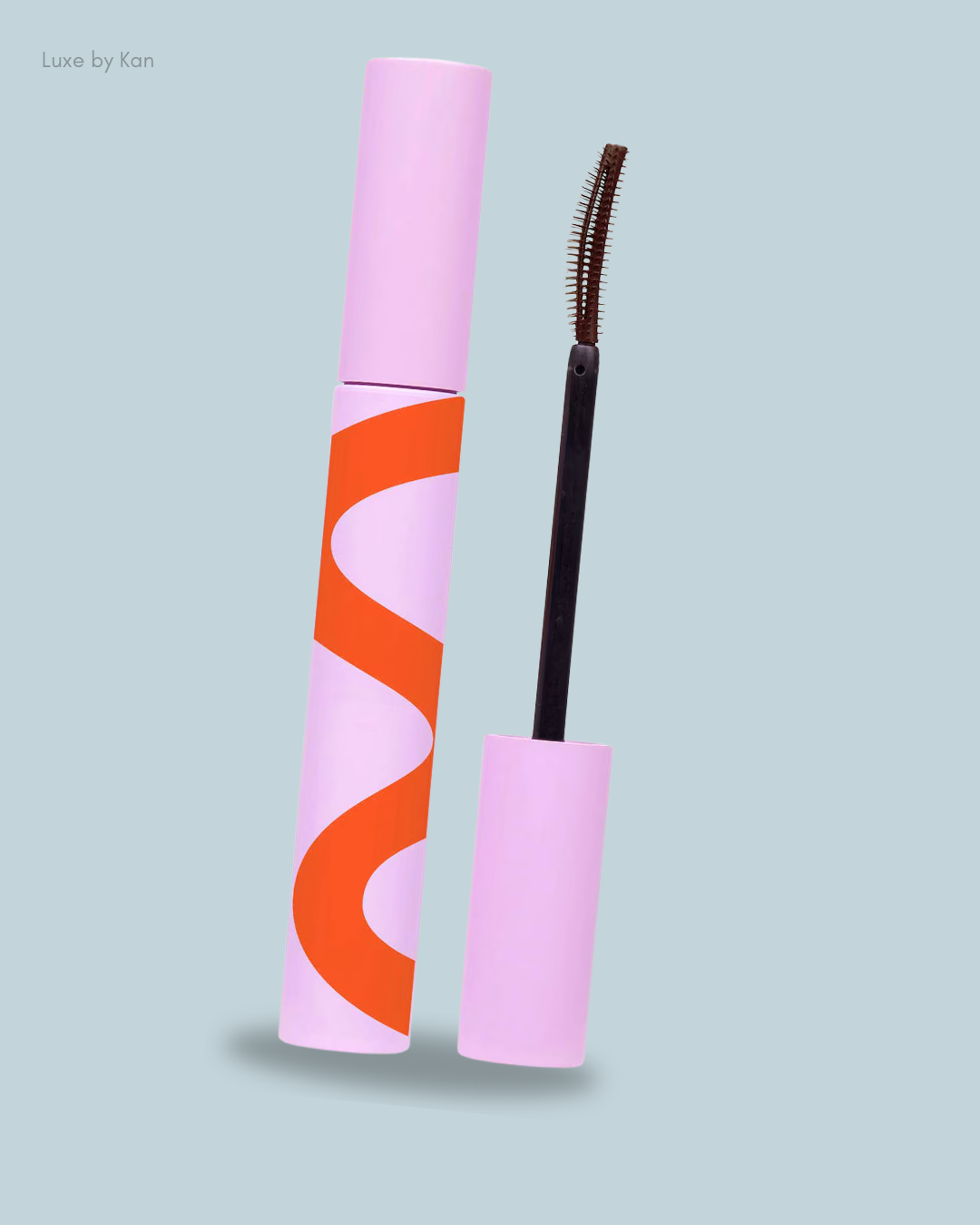 A pink and orange Tower28 MakeWaves Lengthening + Volumizing Mascara tube placed beside its applicator brush.