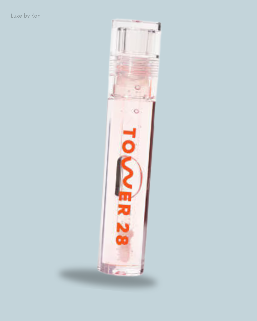 A clear tube of Tower 28 ShineOn Lip Jelly in a light pink shade, featuring an orange logo.