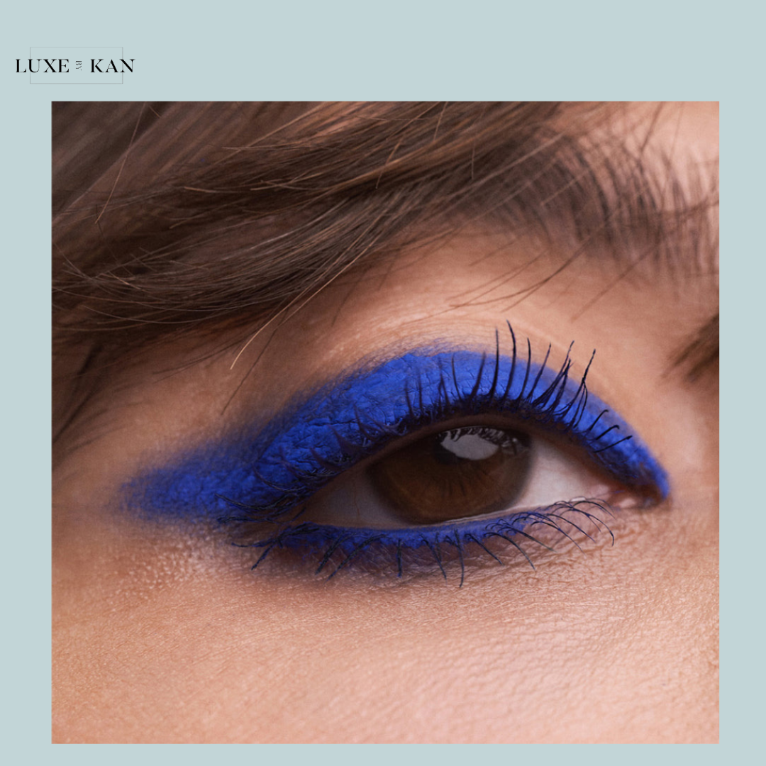 Close-up of a woman's eye featuring bold blue liquid eyeshadow.