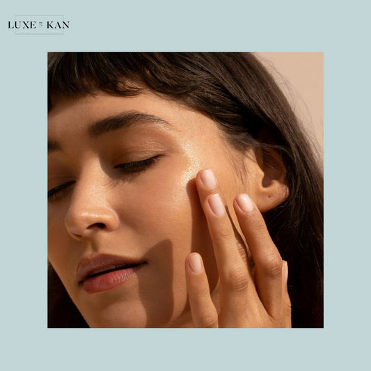 A close-up of a woman's hand touching her face, with soft-focus elements and a light pastel background highlighting her natural elegance.