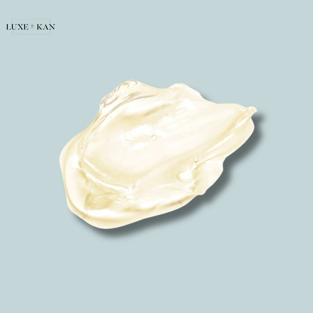 A clear, gel-like skincare product glistens against a soft blue background, showcasing its smooth texture and light golden hue.