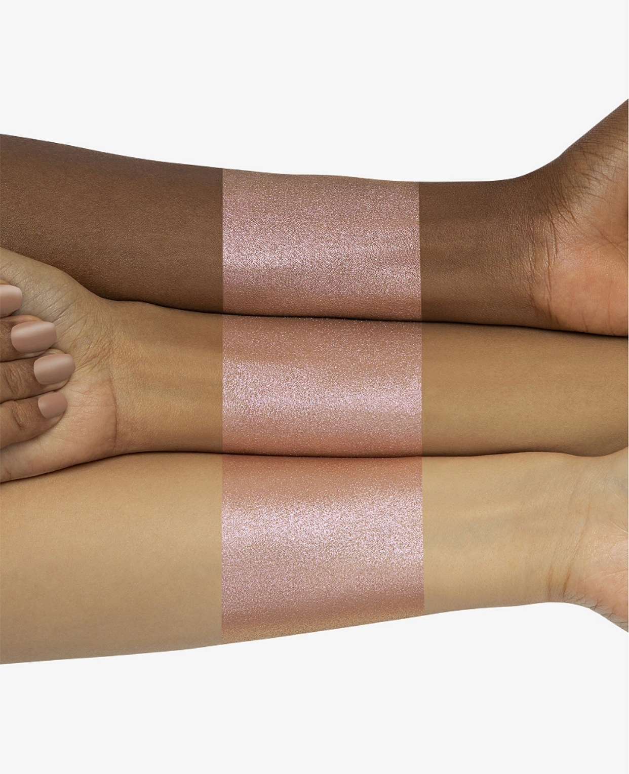 Three arms of different skin tones showcase shimmery pink swatches, highlighting inclusivity in beauty products.
