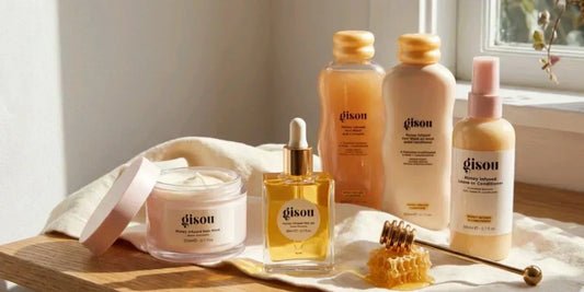 Gisou’s honey-infused mask, oil, and shampoos, some of the best haircare products, on a wooden table in soft light.